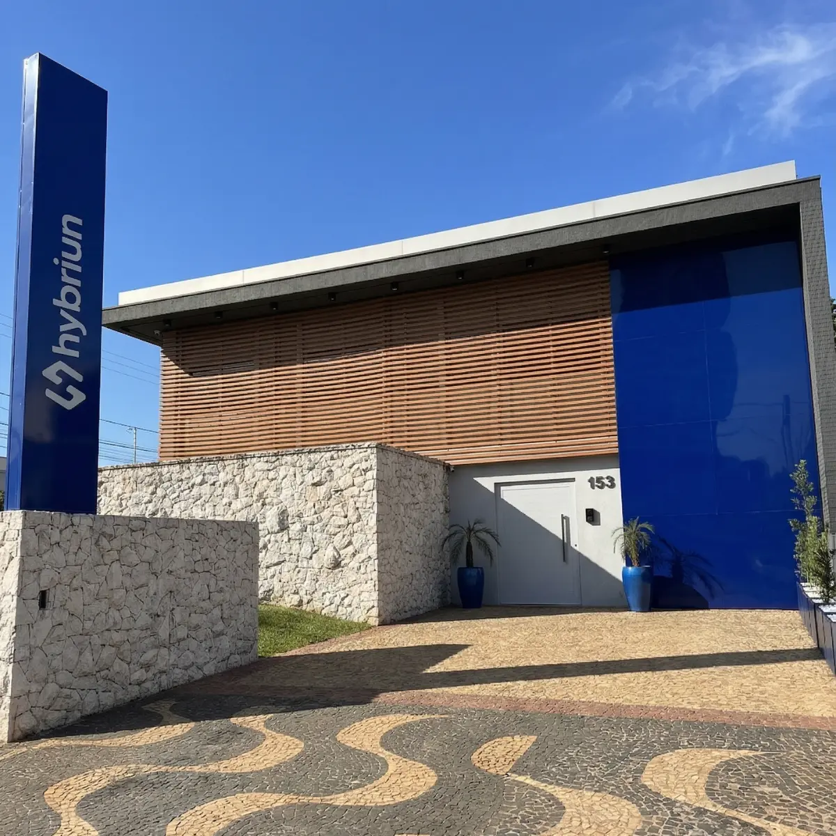 Fachada da sede da Hybriun, com o totem azul da marca na entrada